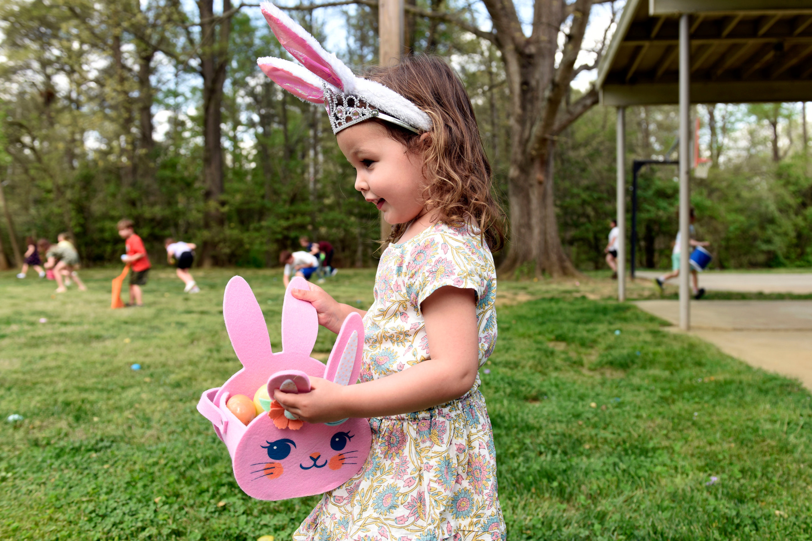 Photo of a Friendly Park child at the 2025 egg hunt wearing bunny ears with a basket